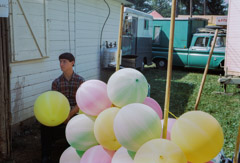 Vivian Maier  -  Location unknown, 1966, (Young man and balloons) / Chromogenic Print  -  10 x 15 on 16 x20 paper
